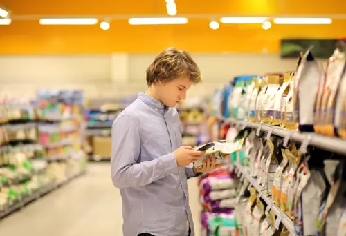 Young man examining food labelling in supermarket