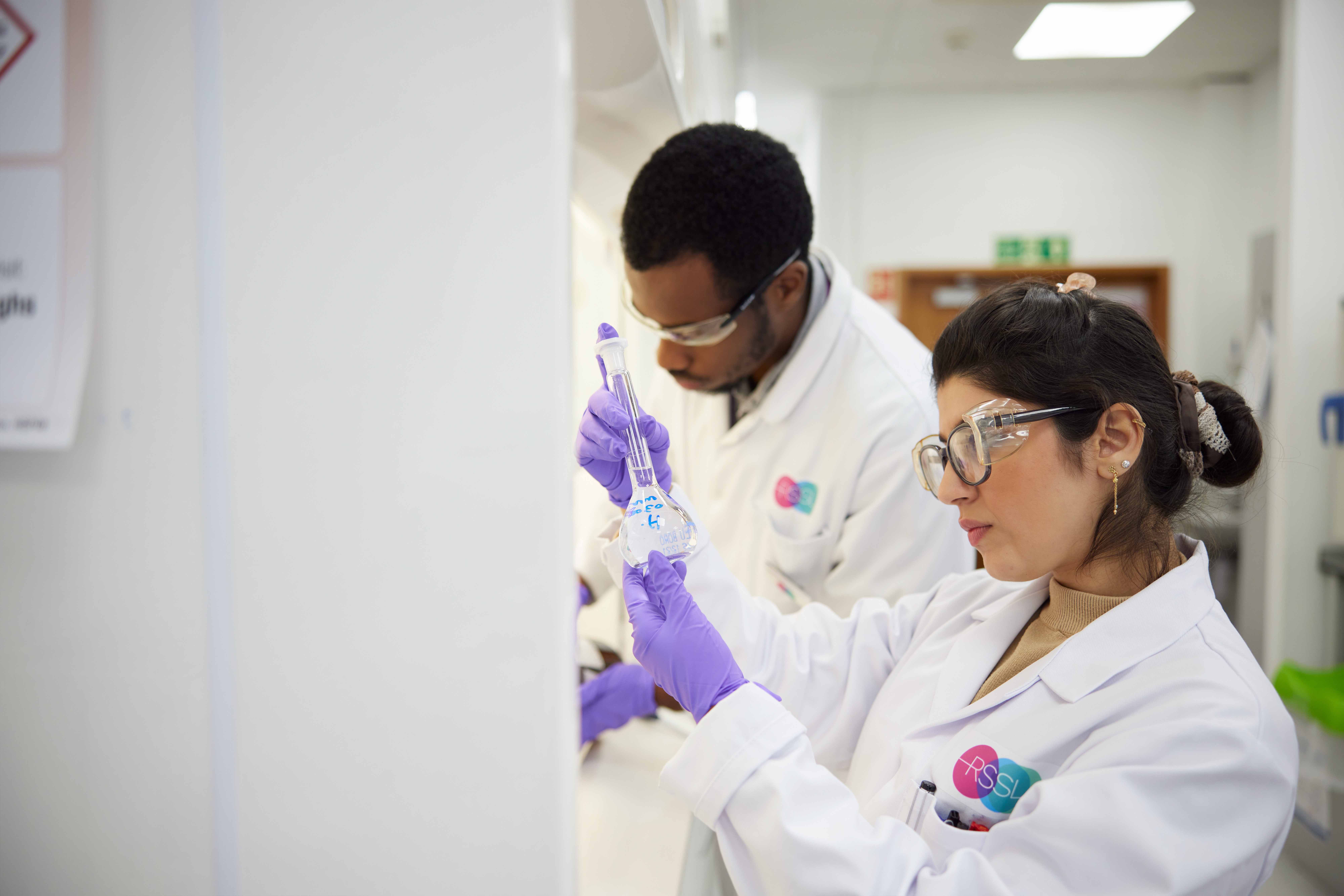 Scientist Examining Flask At Fume Cupboard
